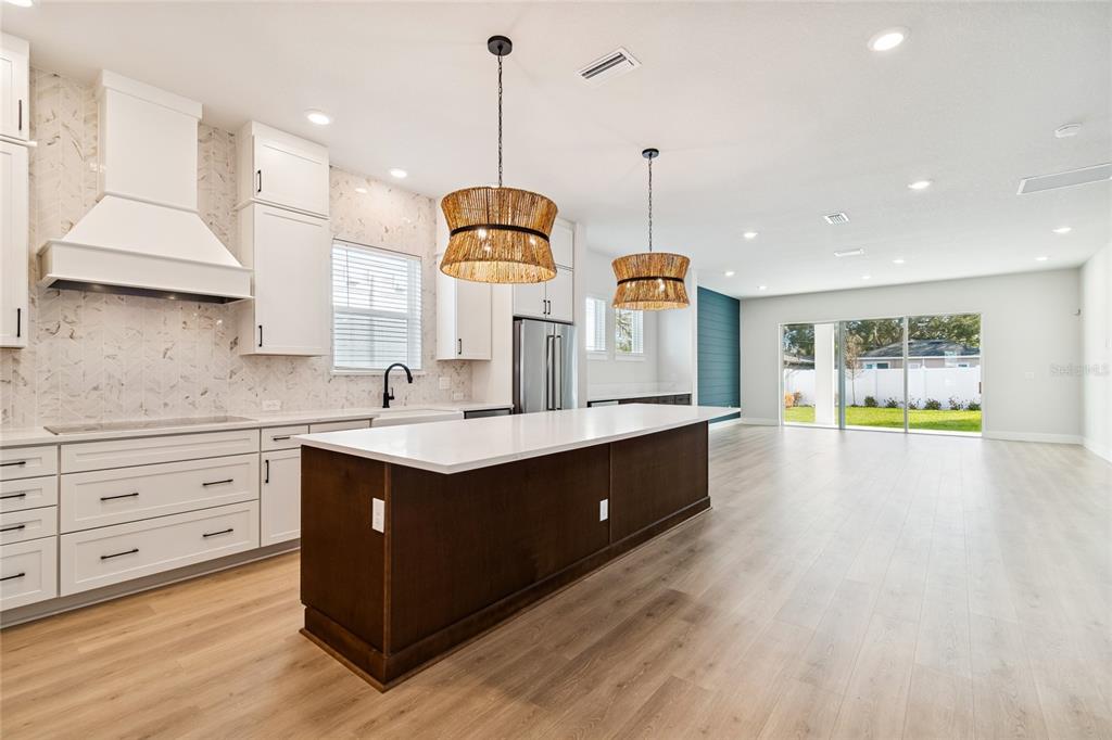 A kitchen features a dark wood island, white cabinetry, and two woven pendant lights — 1104 W OHIO AVENUE, TAMPA, FL