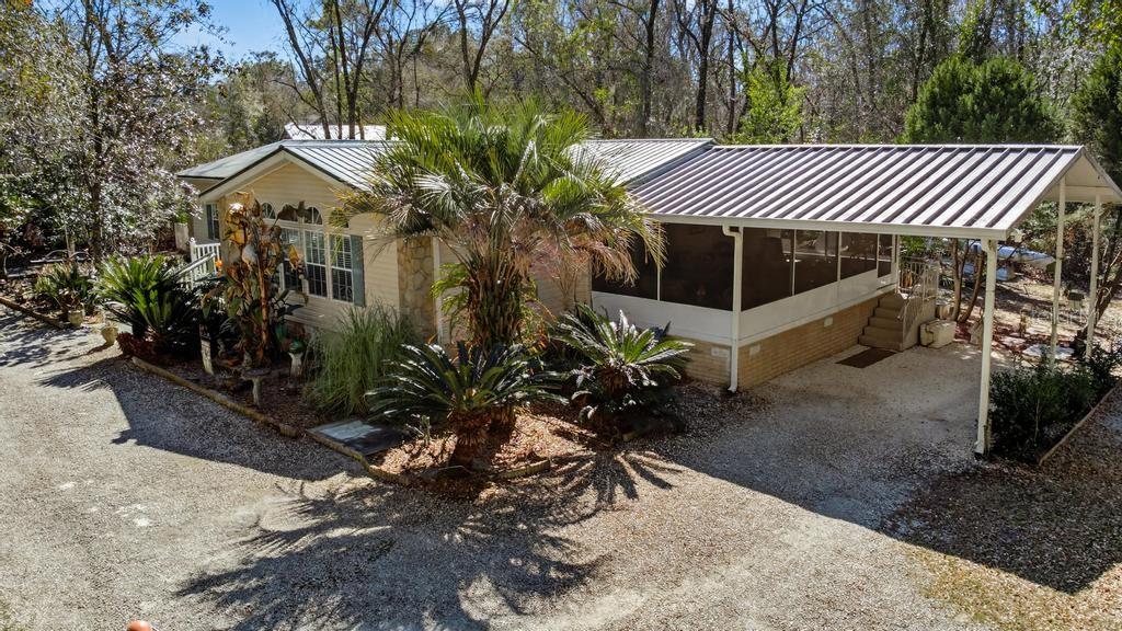 An exterior view of a manufactured home with a metal roof, carport, and screened porch — 8321 HARDWOOD LANDING ROAD, ST AUGUSTINE, FL