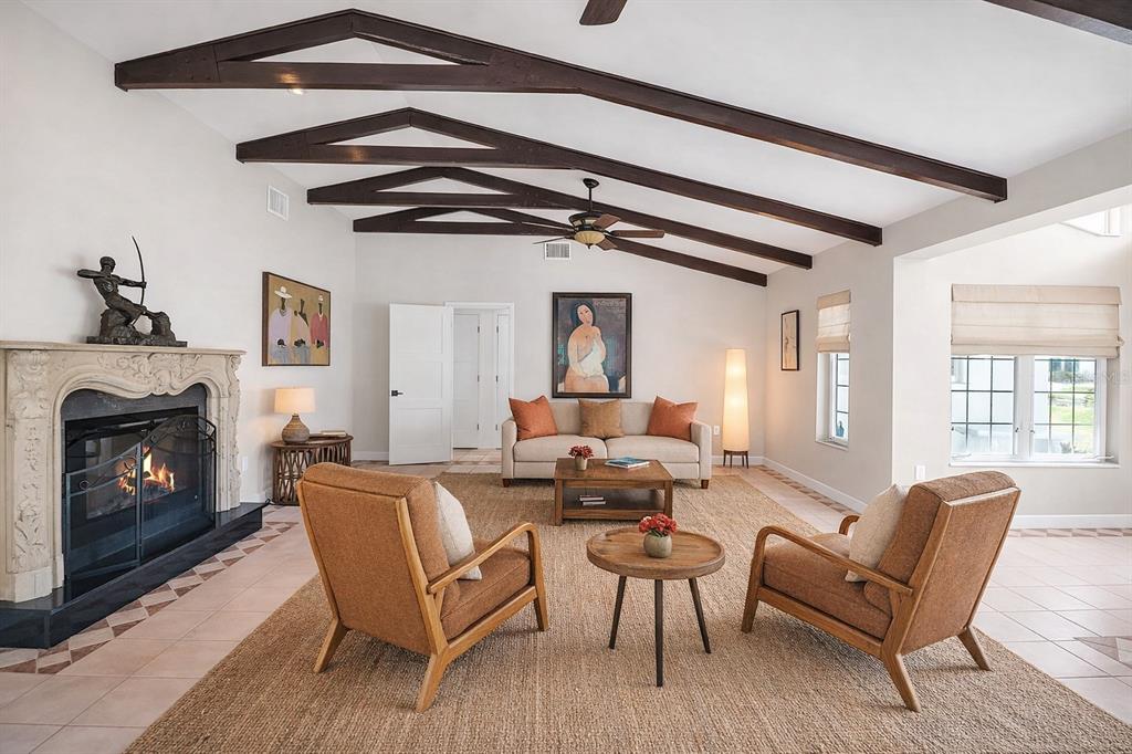 A living room features a vaulted ceiling with exposed beams, a fireplace, and neutral furniture — 608 GARDENIA DRIVE, VENICE, FL