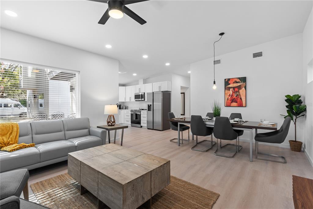 A living and dining area with light wood floors, a grey sofa, and white cabinets — 39 FLORIDA AVENUE, ST AUGUSTINE, FL