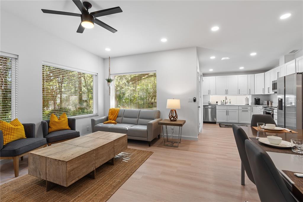 An open-concept living room and kitchen feature light wood floors, white cabinetry, and gray furniture — 39 FLORIDA AVENUE, ST AUGUSTINE, FL