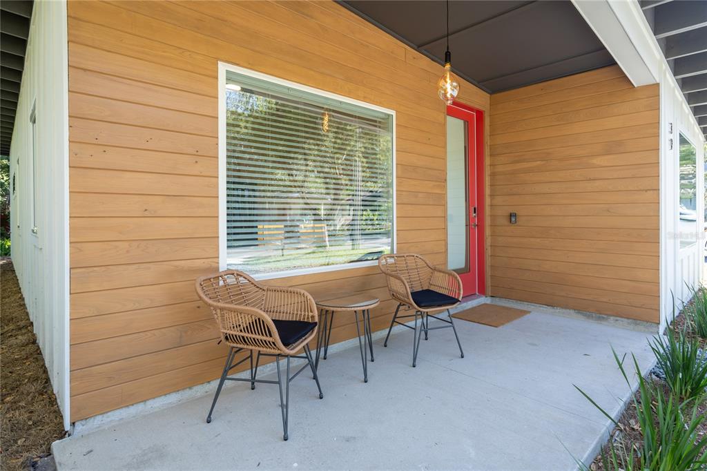 A concrete porch features two wicker chairs, a small table, and a bright red door — 39 FLORIDA AVENUE, ST AUGUSTINE, FL
