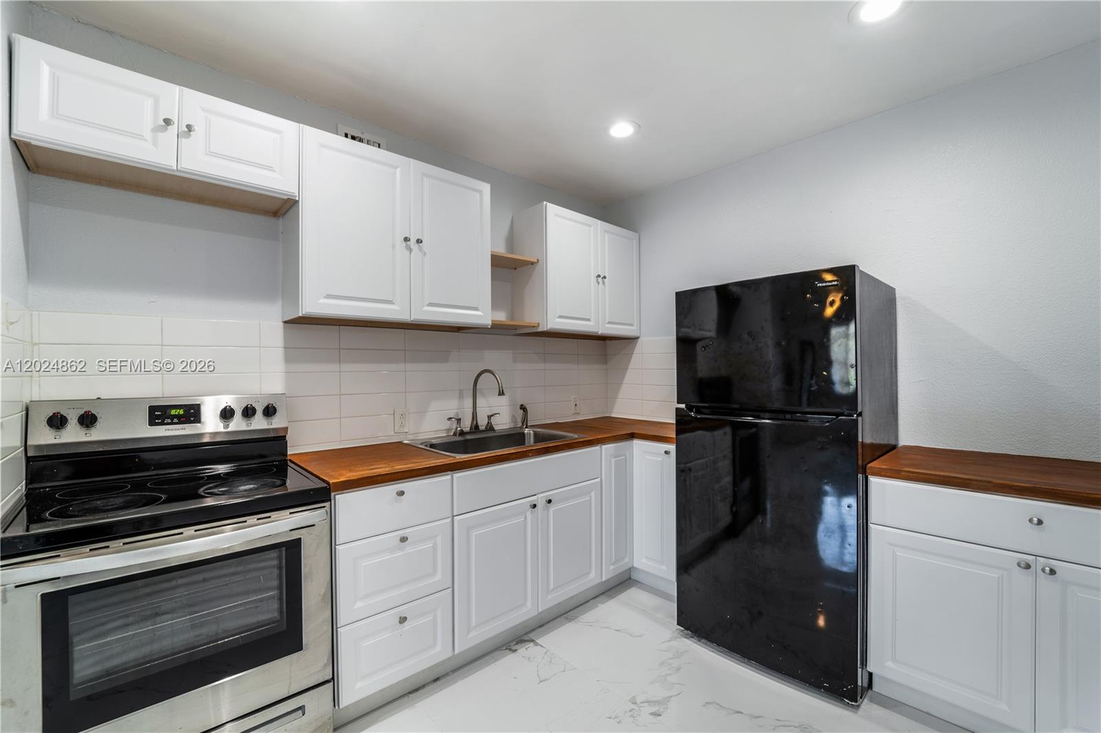 A kitchen features white cabinets, wood countertops, a black refrigerator, and a stainless steel stove — 22300 SW 117th Ave # 4, Miami FL 33170, MIAMI, FL