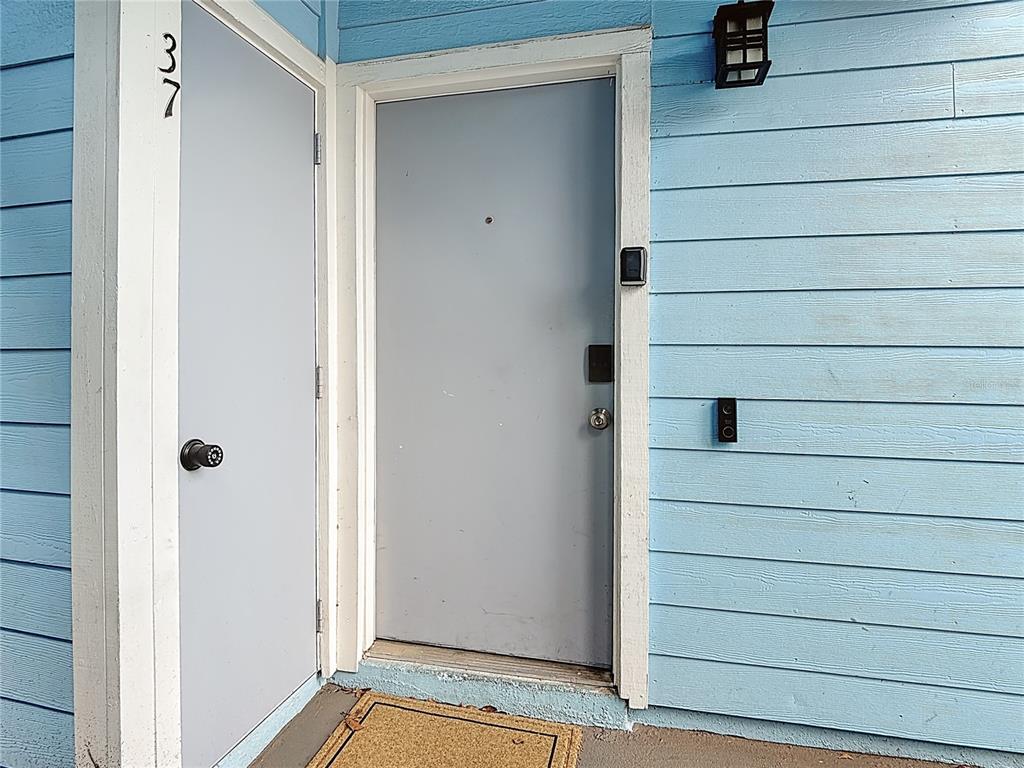 A light blue exterior wall features a front door with a smart lock and keypad — 2753 N POINCIANA BOULEVARD UNIT 37, KISSIMMEE, FL