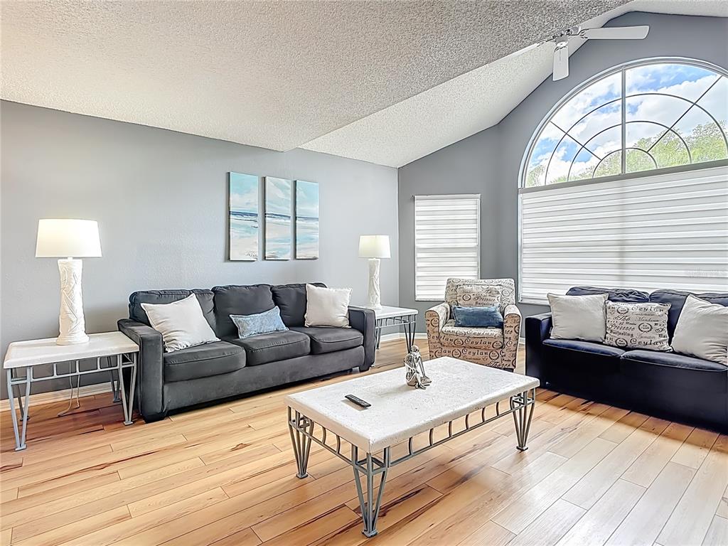 A living room features gray walls, a vaulted ceiling, wood flooring, and two dark sofas — 2753 N POINCIANA BOULEVARD UNIT 37, KISSIMMEE, FL