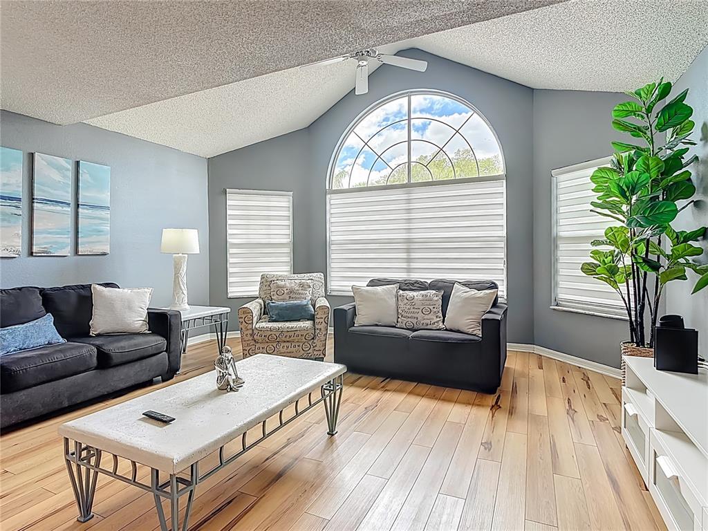 A living room features a vaulted ceiling, light wood floors, and a large arched window — 2753 N POINCIANA BOULEVARD UNIT 37, KISSIMMEE, FL