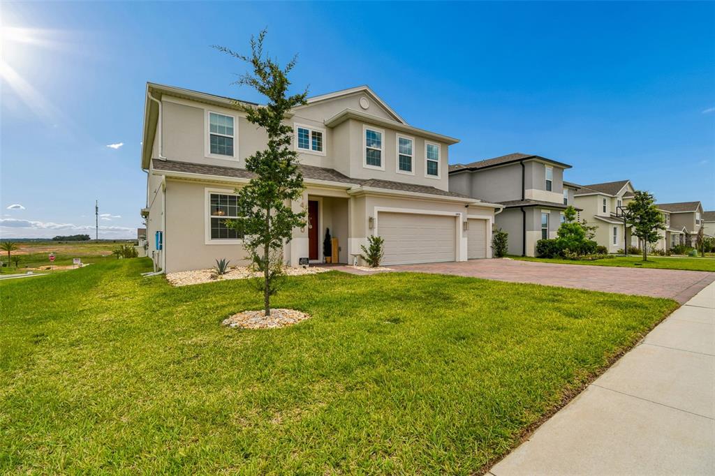 A two-story suburban house with a beige stucco exterior, a paved driveway, and a lawn — 14400 NOTO AVENUE, CLERMONT, FL