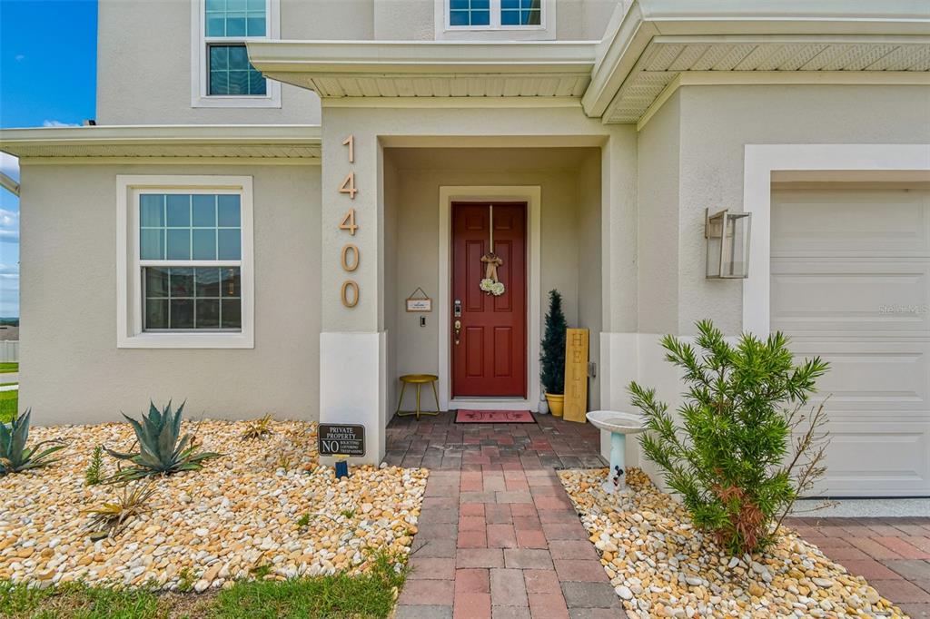 The exterior of a house features a red front door, stone walkway, and rock landscaping — 14400 NOTO AVENUE, CLERMONT, FL