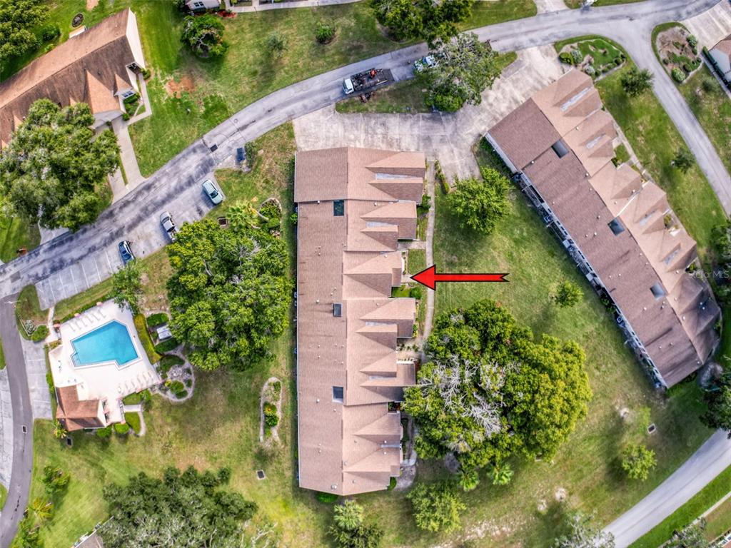An aerial view shows a multi-unit townhouse complex with a red arrow pointing to one unit — 11403 VERSAILLES LANE UNIT E, PORT RICHEY, FL