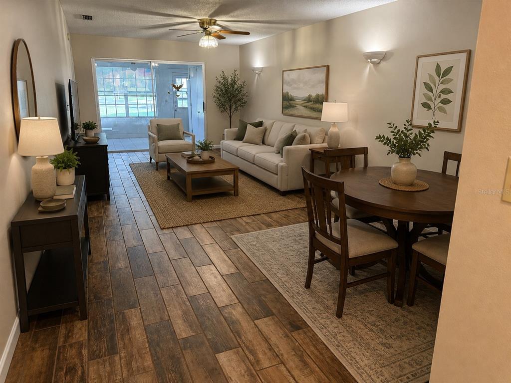 A living room features wood-look tile flooring, a ceiling fan, and a sliding glass door — 11403 VERSAILLES LANE UNIT E, PORT RICHEY, FL