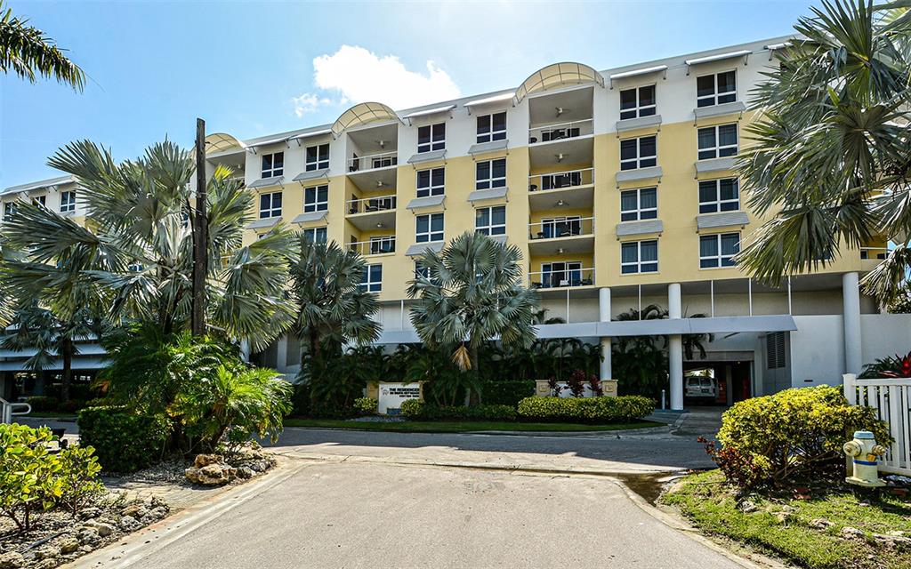 A multi-story apartment building with yellow and white siding stands behind palm trees — 915 SEASIDE DRIVE UNIT 613, Weeks 32-33, SARASOTA, FL