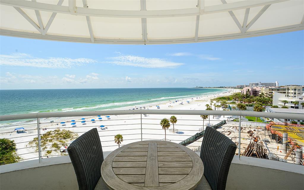 A balcony with a round wooden table and two chairs overlooks a sandy beach and ocean — 915 SEASIDE DRIVE UNIT 613, Weeks 32-33, SARASOTA, FL