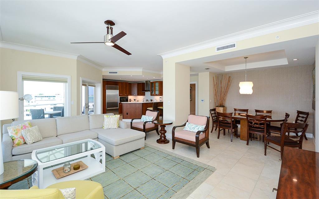 An open-concept living and dining area features tile floors, a sectional sofa, and wood cabinetry — 915 SEASIDE DRIVE UNIT 613, Weeks 32-33, SARASOTA, FL