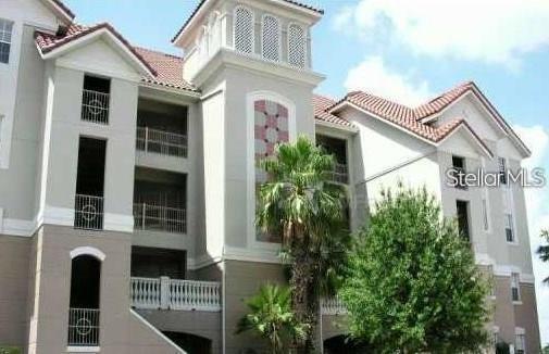 A multi-story apartment building with light-colored stucco walls, balconies, and a red tile roof — 8767 THE ESPLANADE UNIT 42, ORLANDO, FL