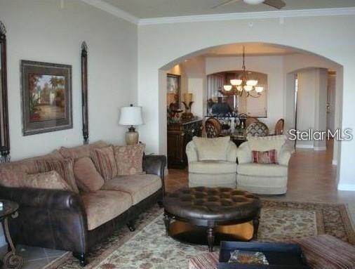 A living room features a brown leather sofa, two beige armchairs, and a round leather ottoman — 8767 THE ESPLANADE UNIT 42, ORLANDO, FL