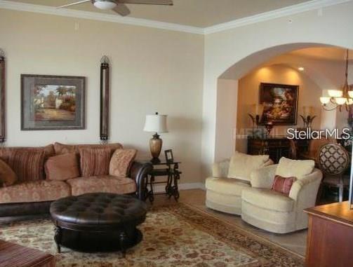 A living room features a brown sofa, two armchairs, a round ottoman, and an arched entryway — 8767 THE ESPLANADE UNIT 42, ORLANDO, FL