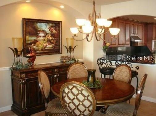 A dining room features a round wooden table, upholstered chairs, a sideboard, and a chandelier — 8767 THE ESPLANADE UNIT 42, ORLANDO, FL