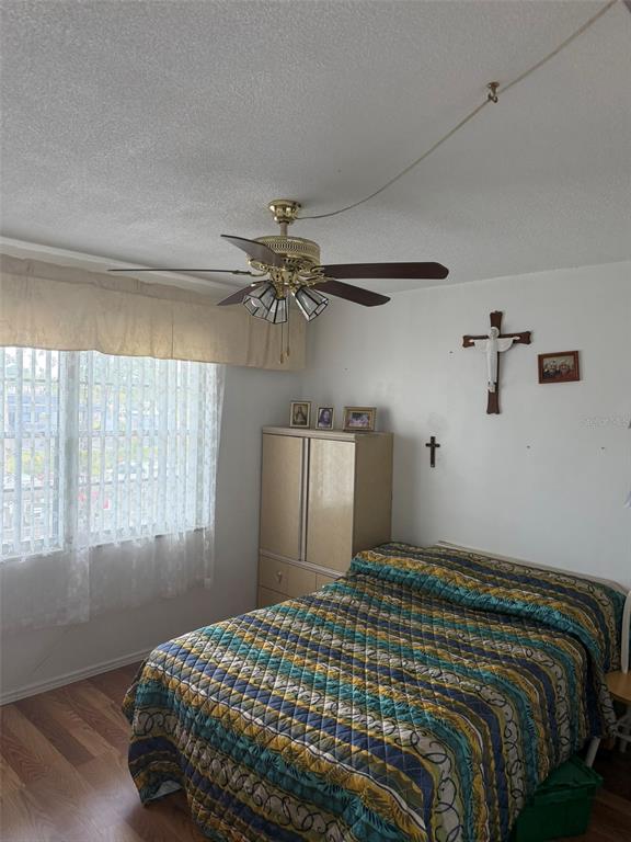 A bedroom features a ceiling fan with an exposed cord, a bed, and wall-mounted crosses — 8100 DR MARTIN LUTHER KING JR STREET N UNIT 208, ST PETERSBURG, FL