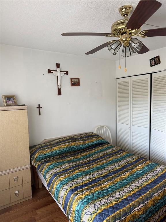 A bedroom features a bed with a patterned quilt, a ceiling fan, and wall-mounted crosses — 8100 DR MARTIN LUTHER KING JR STREET N UNIT 208, ST PETERSBURG, FL