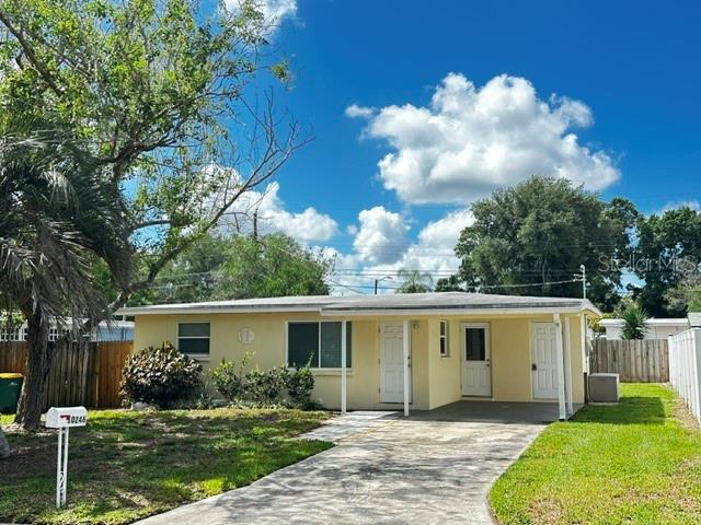 A single-story house with a light yellow exterior, a covered porch, and a concrete driveway — 10246 117TH DRIVE, LARGO, FL