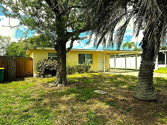 A yellow single-story house features a front yard with trees and a covered carport — 10246 117TH DRIVE, LARGO, FL