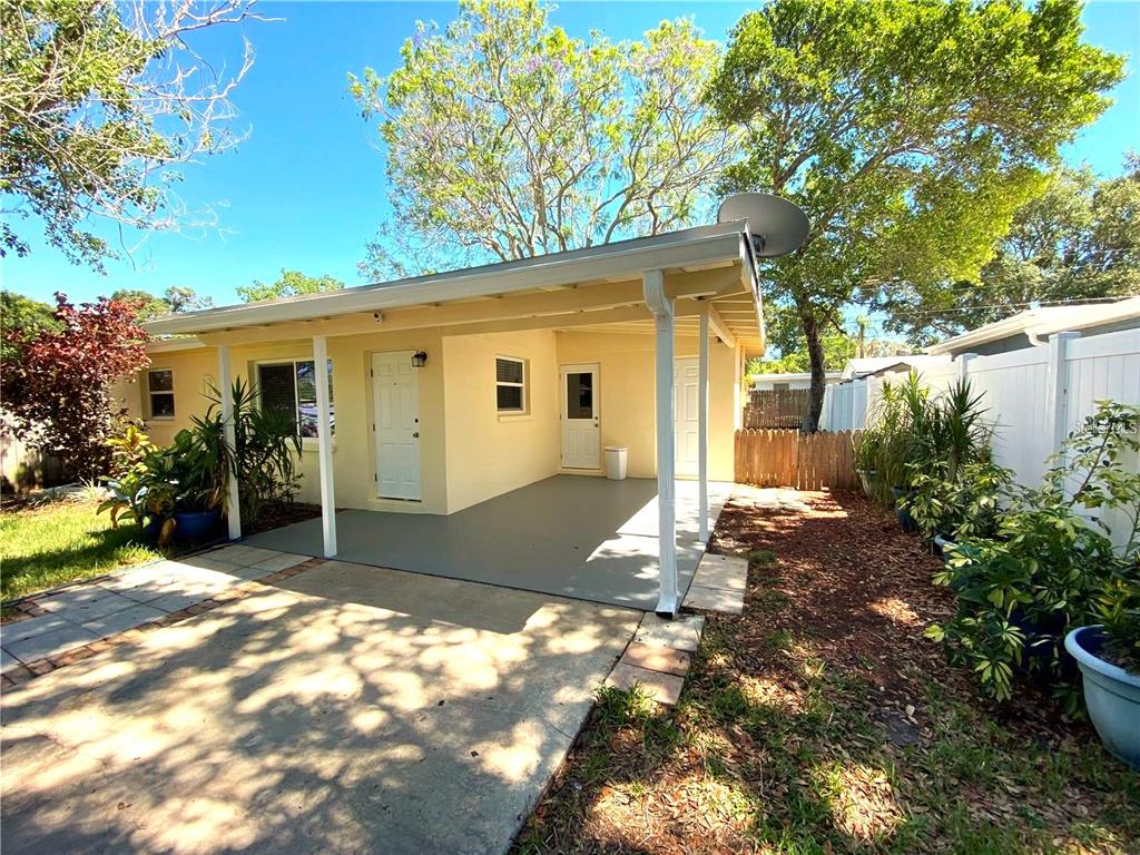 A yellow house exterior features a covered patio, white doors, and a concrete driveway — 10246 117TH DRIVE, LARGO, FL