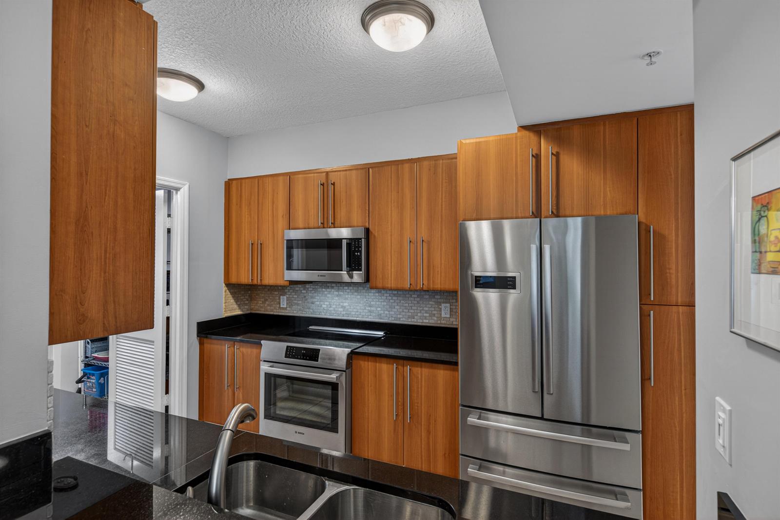 A kitchen features wood cabinets, stainless steel appliances, and black granite countertops — 101 SE 20th Avenue # 201, Deerfield Beach FL 33441, DEERFIELD BEACH, FL