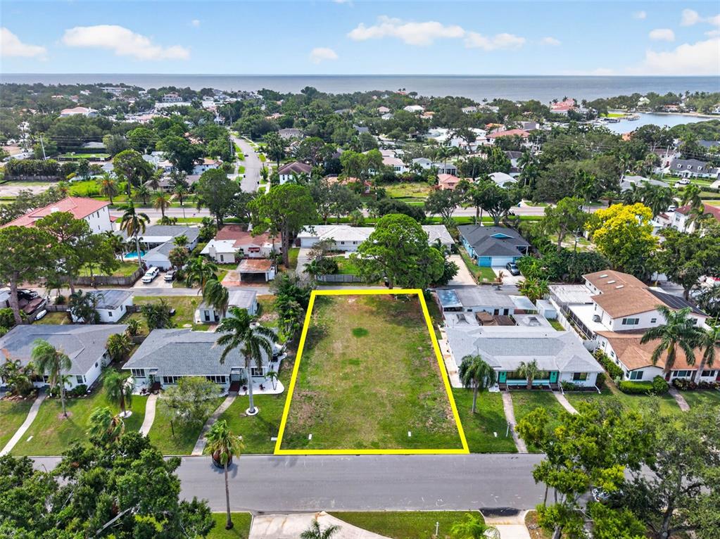 An aerial view shows a vacant, rectangular residential lot outlined in yellow between two houses — 257 MATEO WAY NE, ST PETERSBURG, FL