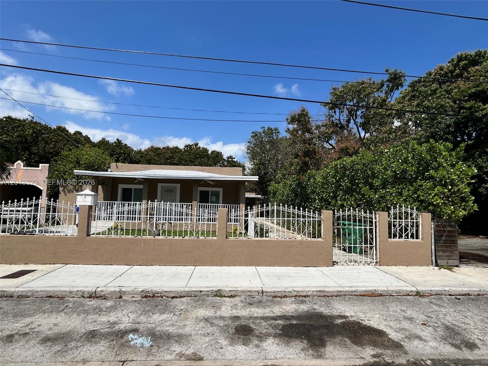A single-story house with a white metal fence and a concrete wall sits behind a sidewalk — 261 NW 49th St # A, Miami FL 33127, MIAMI, FL