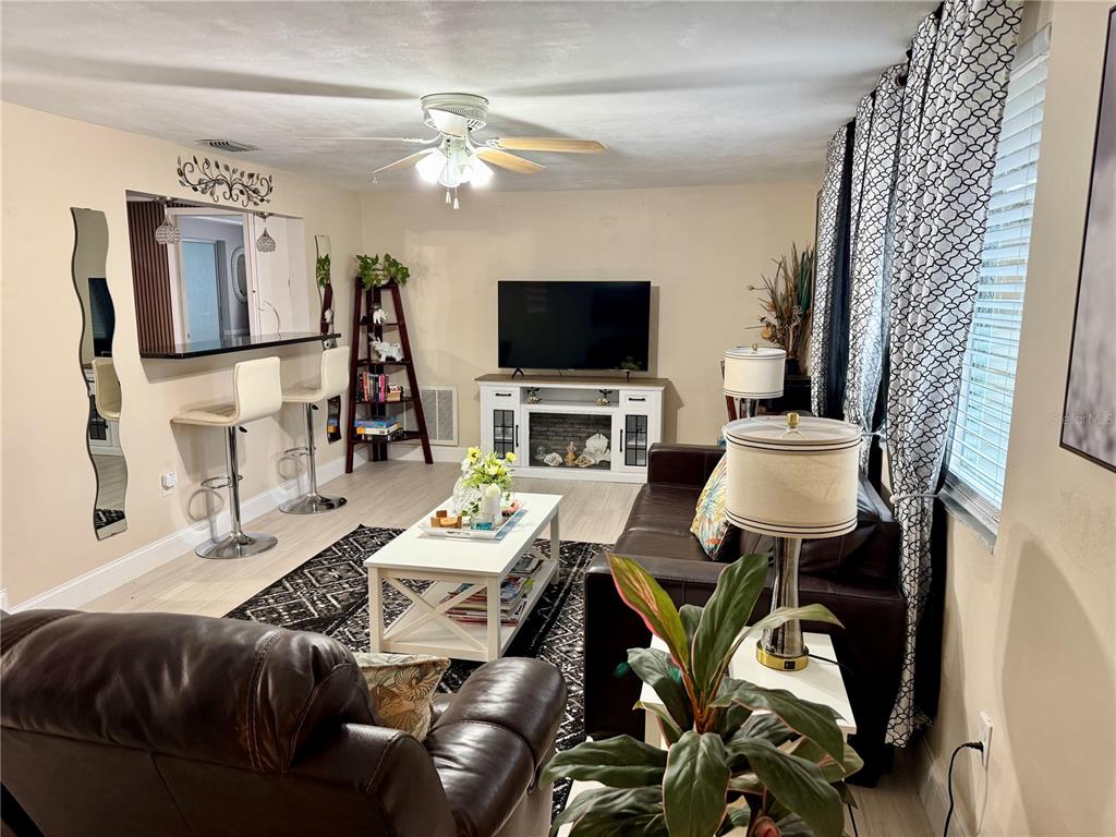 A living room features a television, a breakfast bar with stools, and dark leather furniture — 3625 RICHBORO DRIVE, HOLIDAY, FL