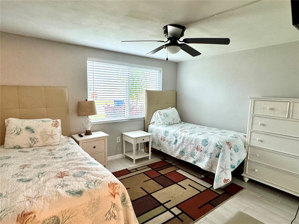 A bedroom features two twin beds, a dresser, a ceiling fan, and a patterned rug — 3625 RICHBORO DRIVE, HOLIDAY, FL