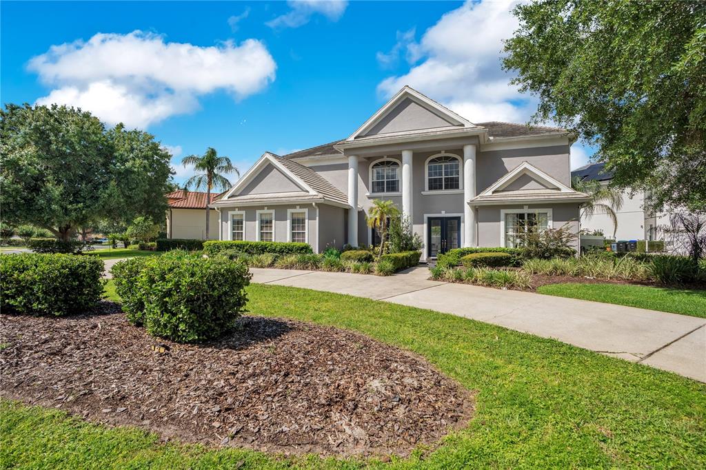 A two-story house with a gray exterior, white columns, and a concrete driveway — 10760 EMERALD CHASE DRIVE, ORLANDO, FL