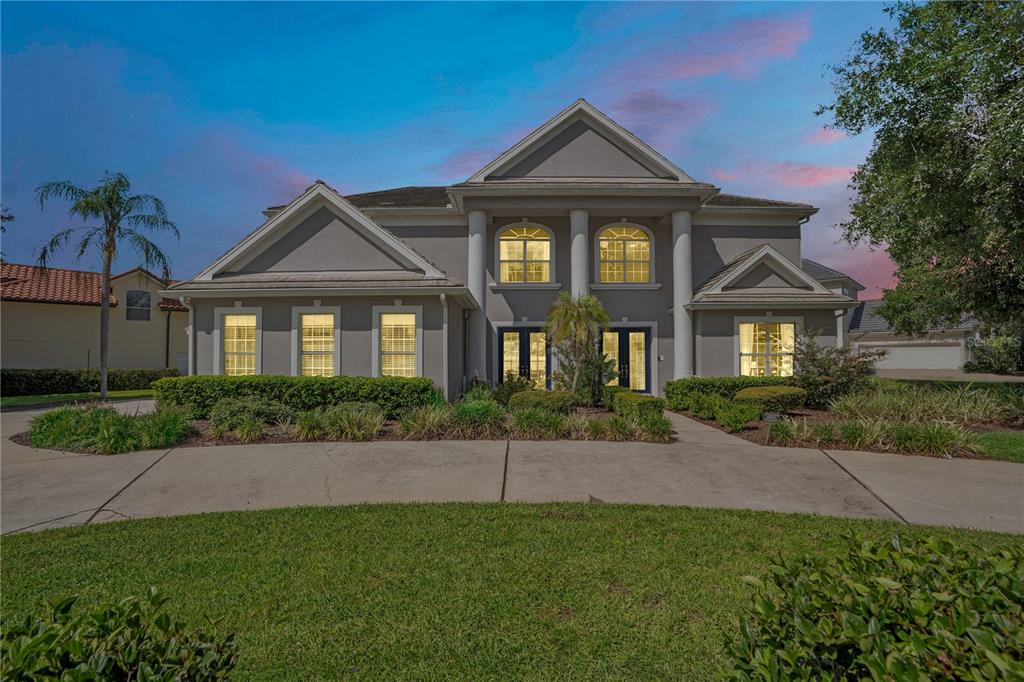 A two-story gray house with a columned entryway and a curved concrete driveway — 10760 EMERALD CHASE DRIVE, ORLANDO, FL