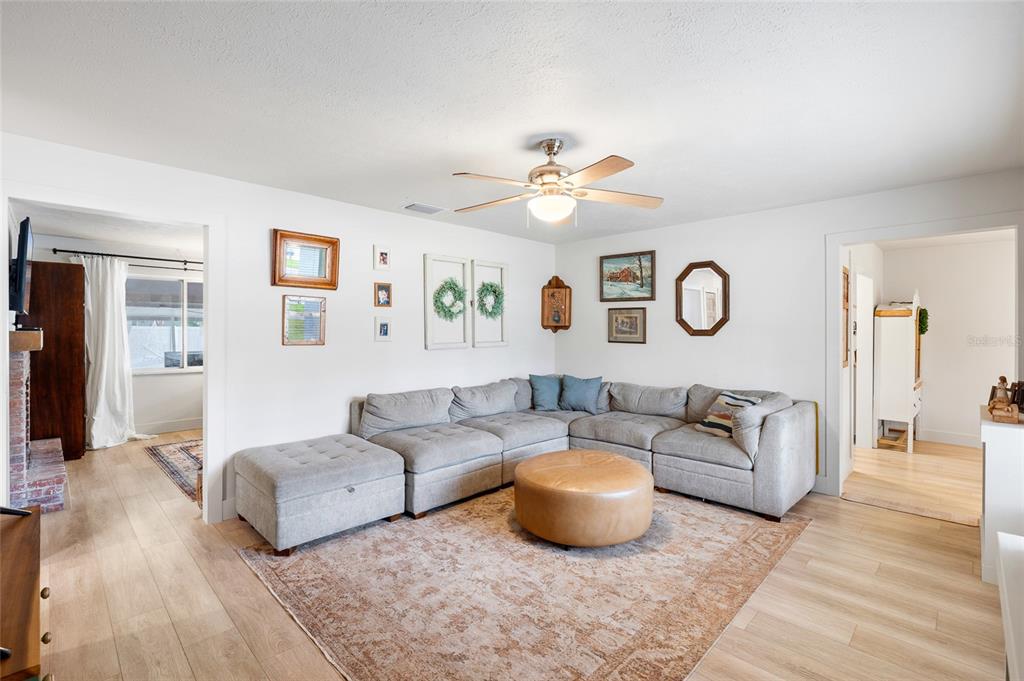 A living room features a large grey sectional sofa, a leather ottoman, and wall decor — 8212 SUNNY VALE PLACE, TAMPA, FL