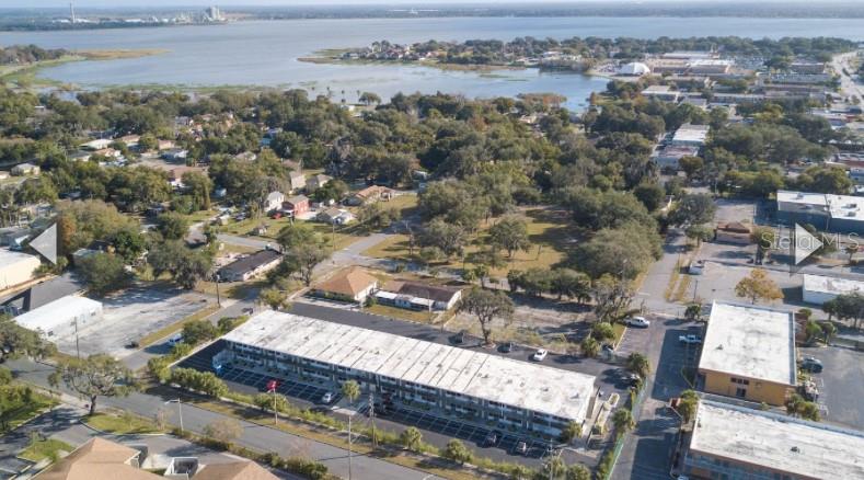 An aerial view shows a multi-story apartment building with a parking lot near a lake — 515 BON AIR STREET UNIT 130, LAKELAND, FL