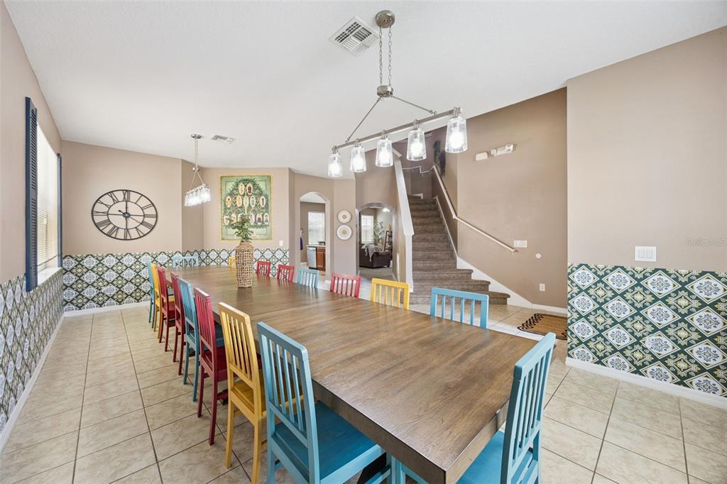 A dining room features a long wooden table with colorful chairs and patterned wallpaper — 4460 NIRVANA PARKWAY, KISSIMMEE, FL