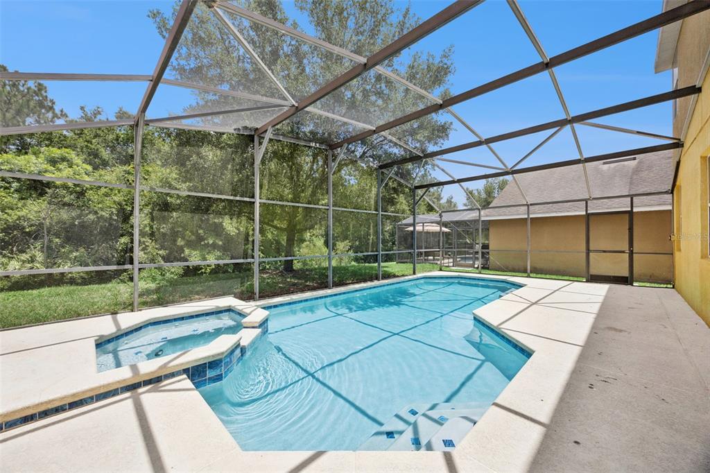 An outdoor swimming pool and spa enclosed by a screened lanai next to a house — 4460 NIRVANA PARKWAY, KISSIMMEE, FL