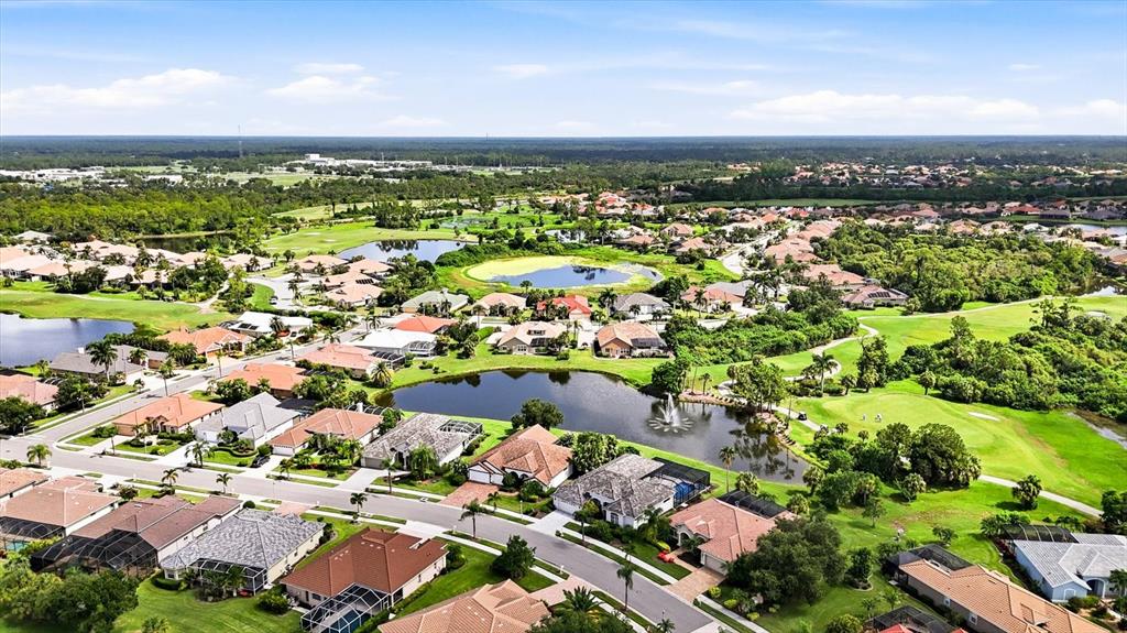 An aerial view shows a residential neighborhood with houses surrounding several ponds and a golf course — 5236 PINE SHADOW LANE, NORTH PORT, FL
