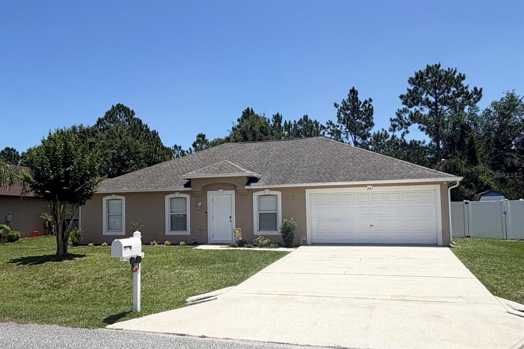A single-story house with a tan exterior, a two-car garage, and a concrete driveway — 14 LEE DRIVE, PALM COAST, FL