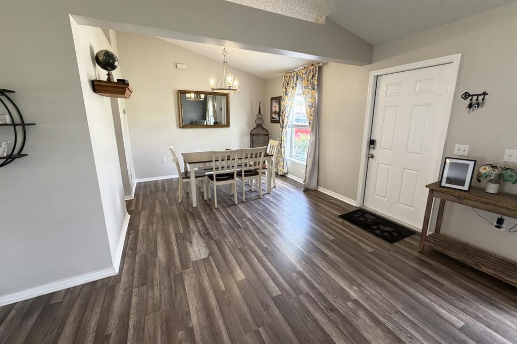 A dining area with wood-look flooring, a chandelier, and an adjacent entryway with a door — 14 LEE DRIVE, PALM COAST, FL