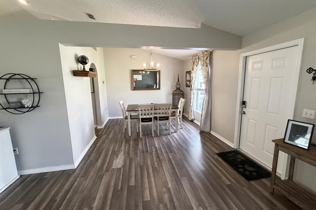 A dining area features wood-look flooring, a chandelier, and a table with four chairs — 14 LEE DRIVE, PALM COAST, FL