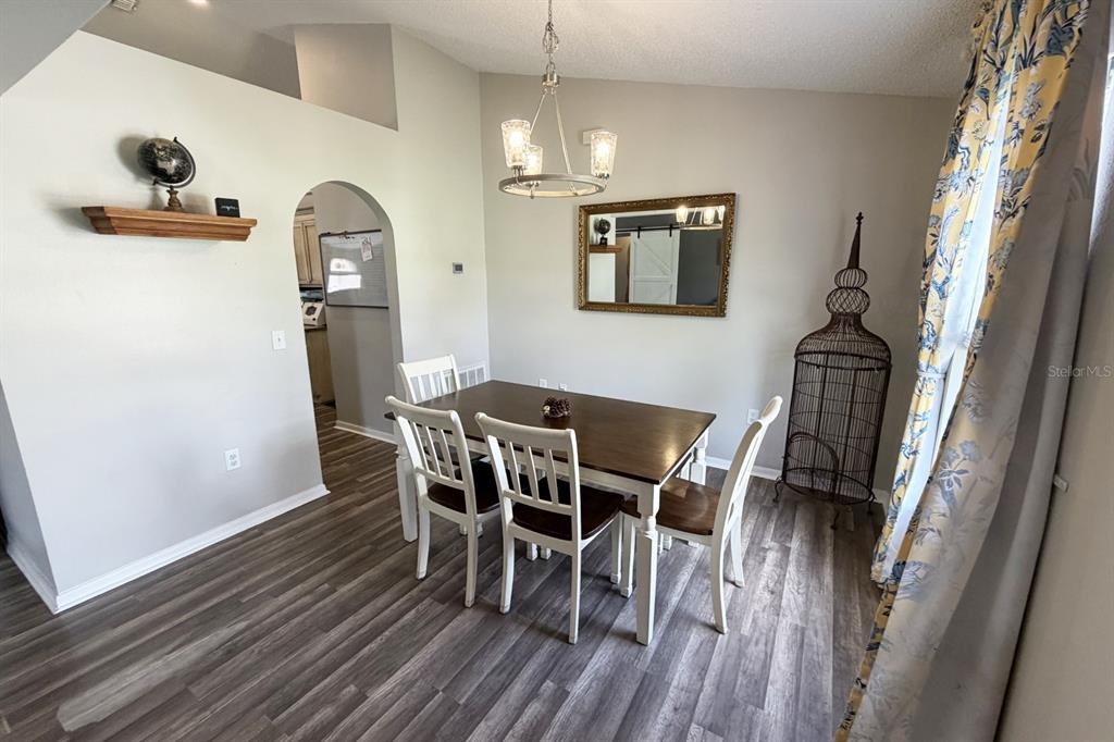 A dining room features a wooden table with four chairs, a chandelier, and wood-look flooring — 14 LEE DRIVE, PALM COAST, FL