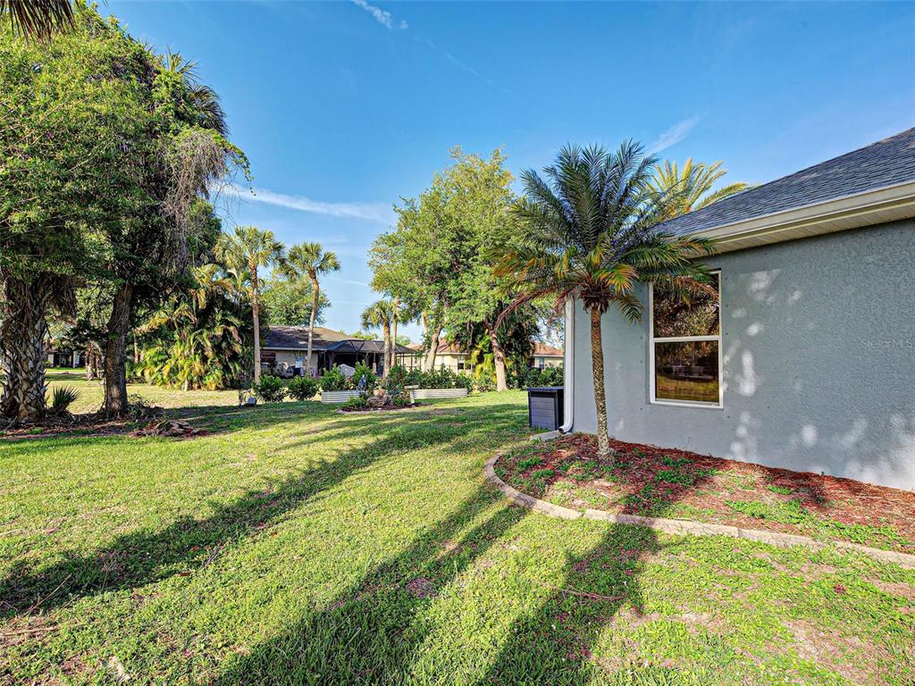 A view of a grassy backyard with a palm tree and the side of a house — 329 BAHIA BLANCA DRIVE, PUNTA GORDA, FL