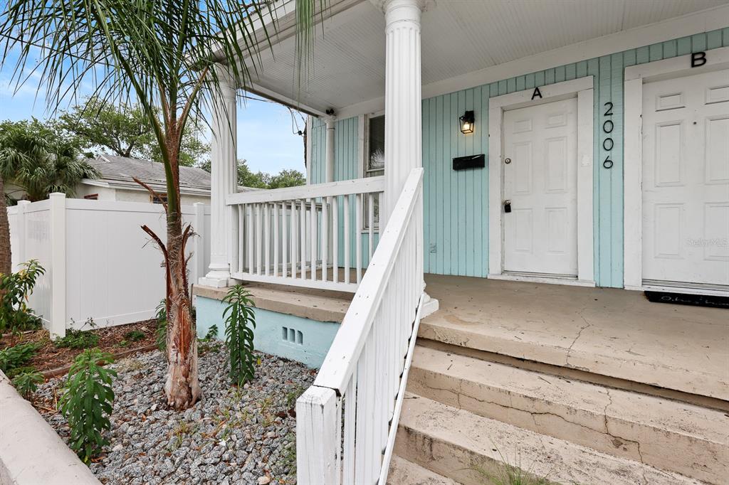 A light blue duplex exterior features a covered porch with white railings and stairs — 2006 E COLUMBUS DRIVE UNIT A, TAMPA, FL