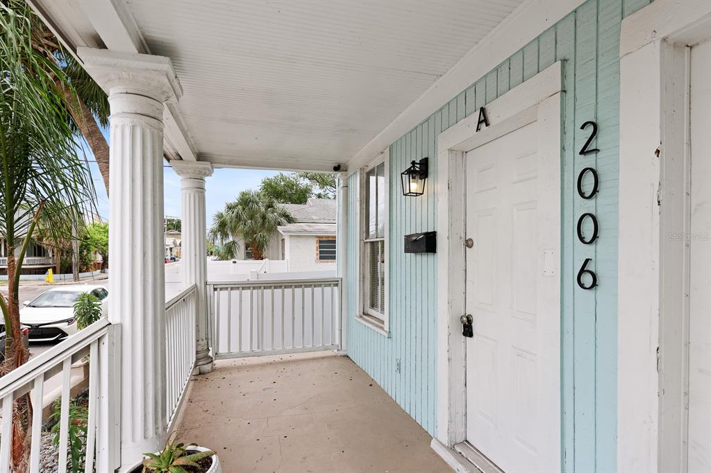 A covered front porch features light blue vertical siding, white columns, and a white door — 2006 E COLUMBUS DRIVE UNIT A, TAMPA, FL