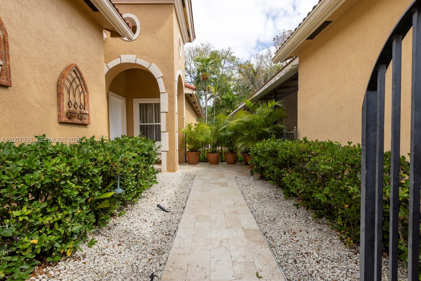 A stone walkway leads through a landscaped courtyard between two tan stucco building wings — 12159 NW 59th St, Coral Springs FL 33076, CORAL SPRINGS, FL
