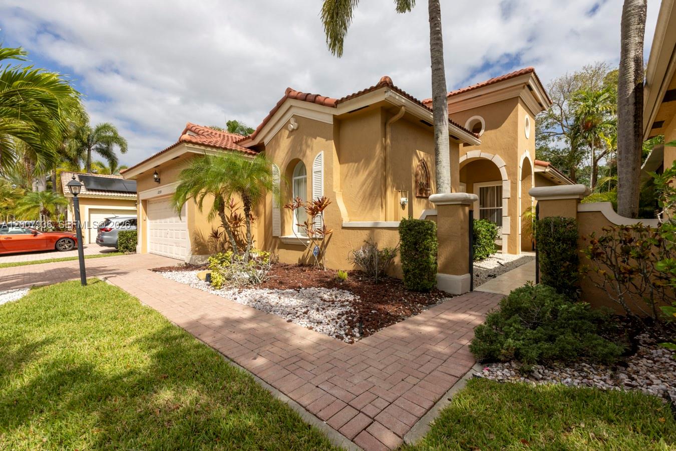 A tan stucco house with a tiled roof features a paved walkway and landscaped yard — 12159 NW 59th St, Coral Springs FL 33076, CORAL SPRINGS, FL