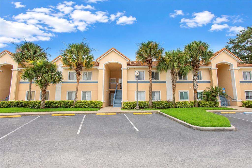 A two-story apartment building with tan stucco walls, a tiled roof, and palm trees — 508 VILLA DEL SOL CIRCLE UNIT 204, ORLANDO, FL