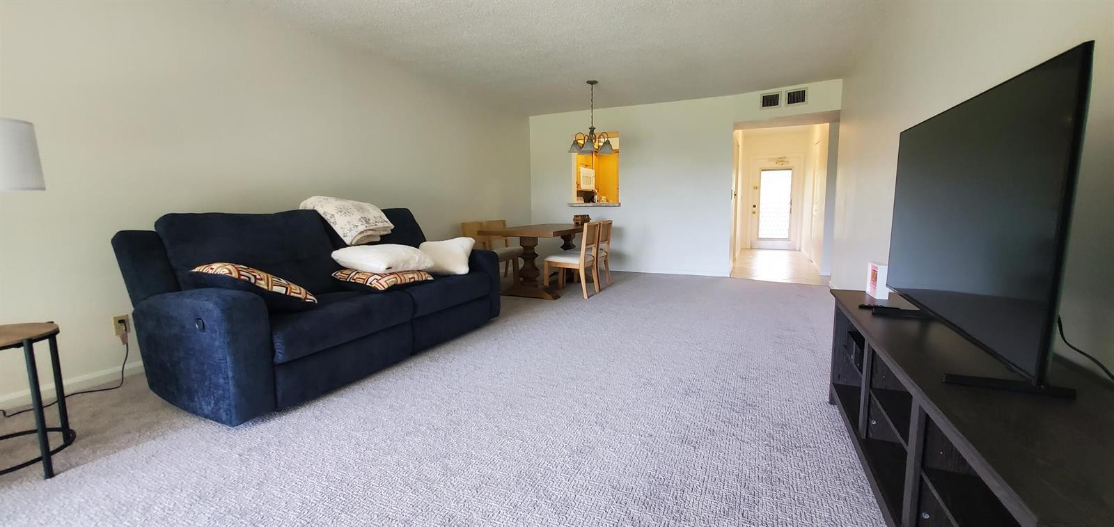 A living room features a blue sofa, a dining table, and a television on a stand — 260 NW 76th Avenue # 201, Margate FL 33063, MARGATE, FL