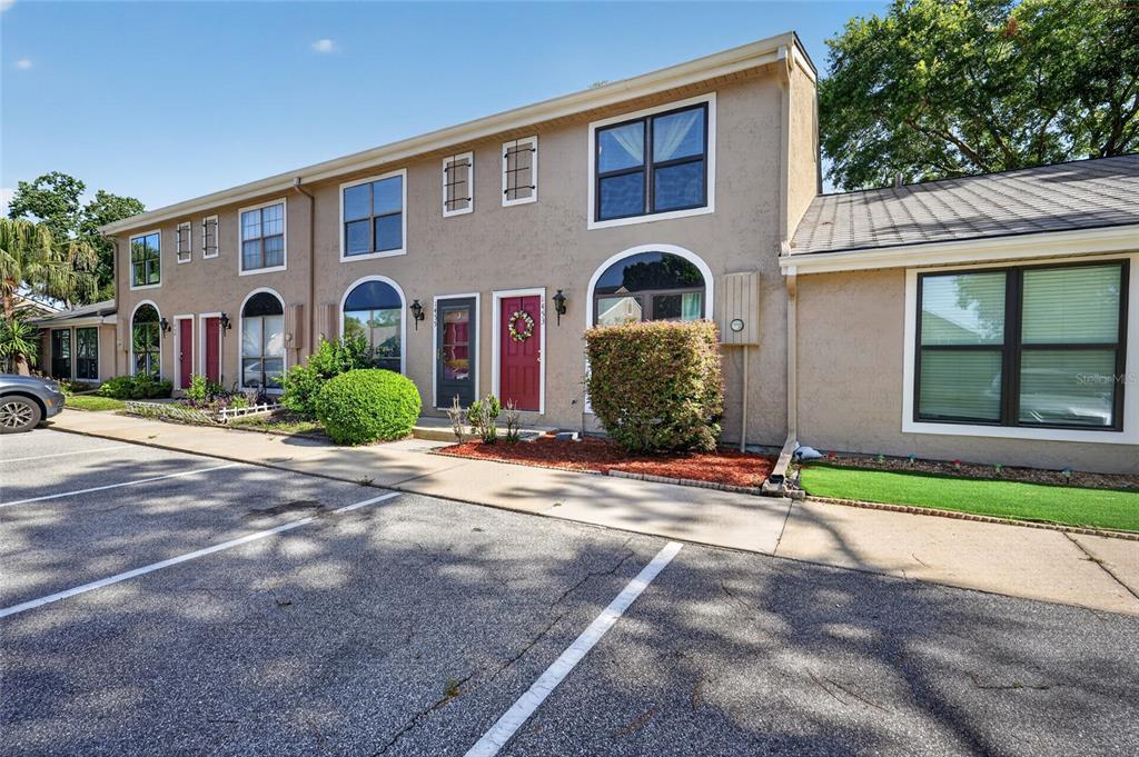 A two-story tan townhouse exterior with a parking lot in the foreground — 1453 CASA PARK CIRCLE, WINTER SPRINGS, FL